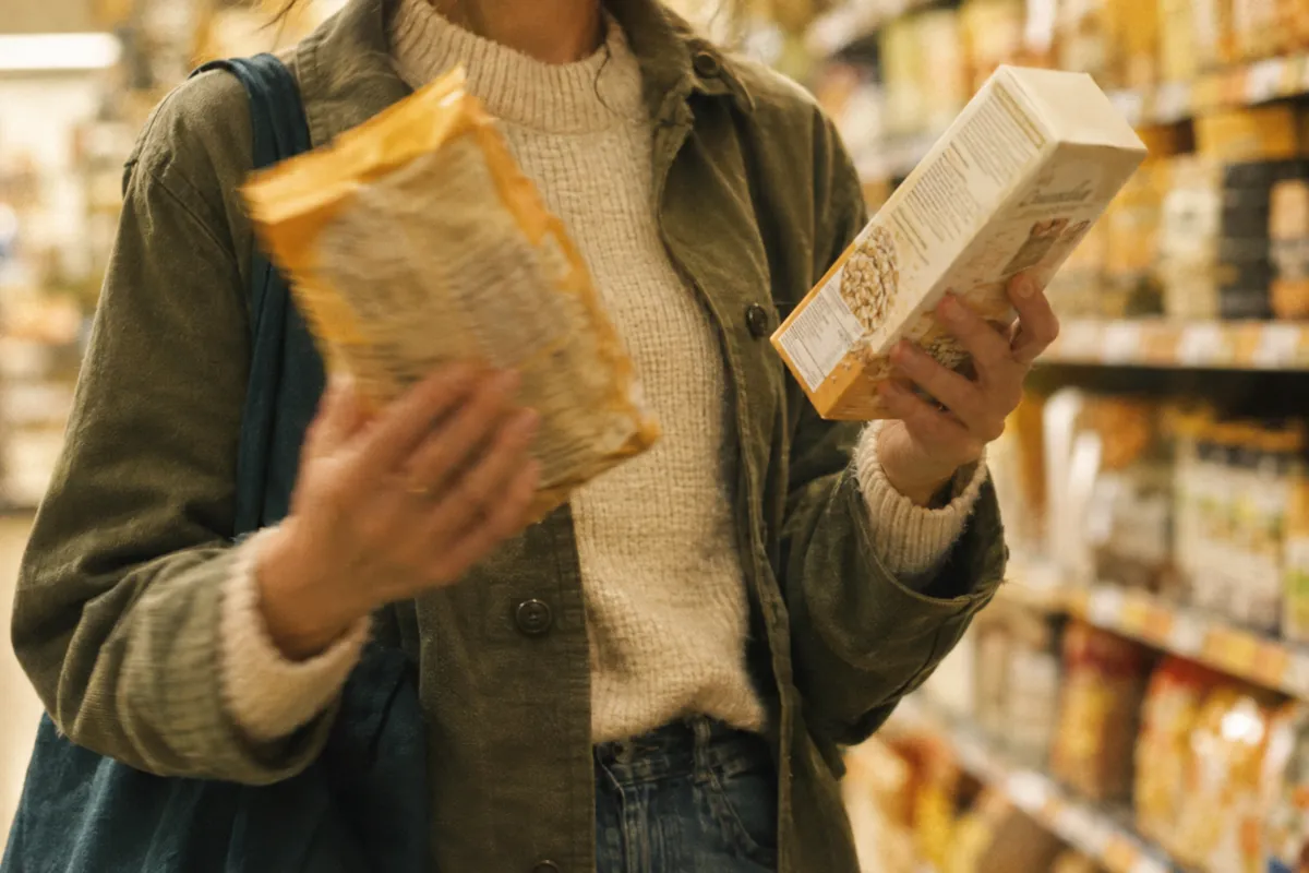 A shopper in a grocery aisle comparing two food packages